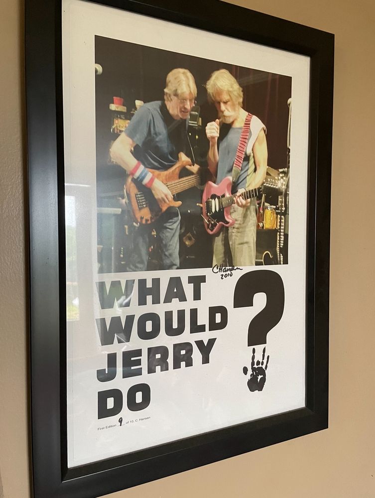 Phil Lesh (with a Modulus bass)and Bob Weir (with his pink Fender Stratocaster)speaking privately with the caption “what would Jerry do?” The question mark has a Jerry handprint in place of the dot. 