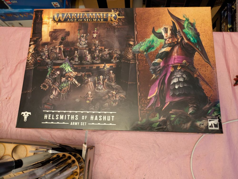 The Helsmiths of Hashut Army Set box on a pink table. 
