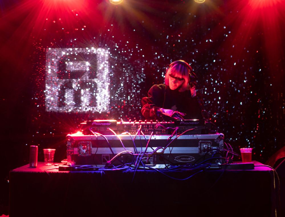 Janus Rose DJing with the Aftermath logo behind her