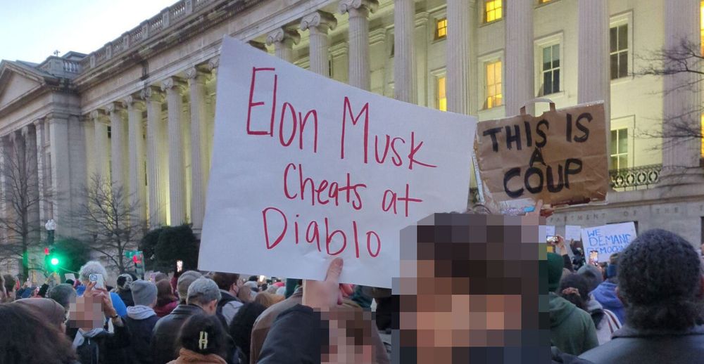 A protester holding an "Elon Musk cheats at Diablo" sign