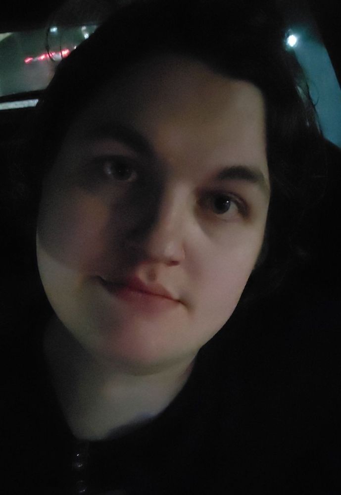 A picture of a woman in her mid thirties. There are shadows playing across her face in the rainy night. 