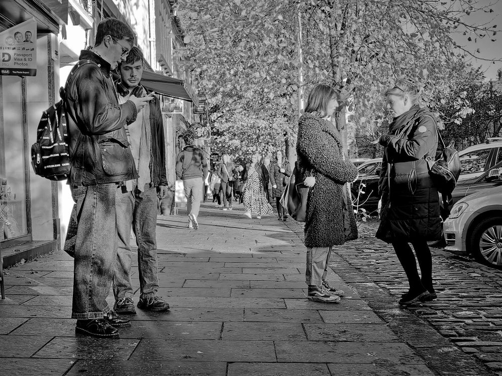 Black and white photo of two pairs of people on a pavement. One pair of young men looking at a mobile phone screen, the other, two women, in conversation.

Olympus E-M10MarkII
LUMIX G VARIO 12-32/F3.5-5.6
@ƒ/3.5 12.0 mm 1/200s ISO200
