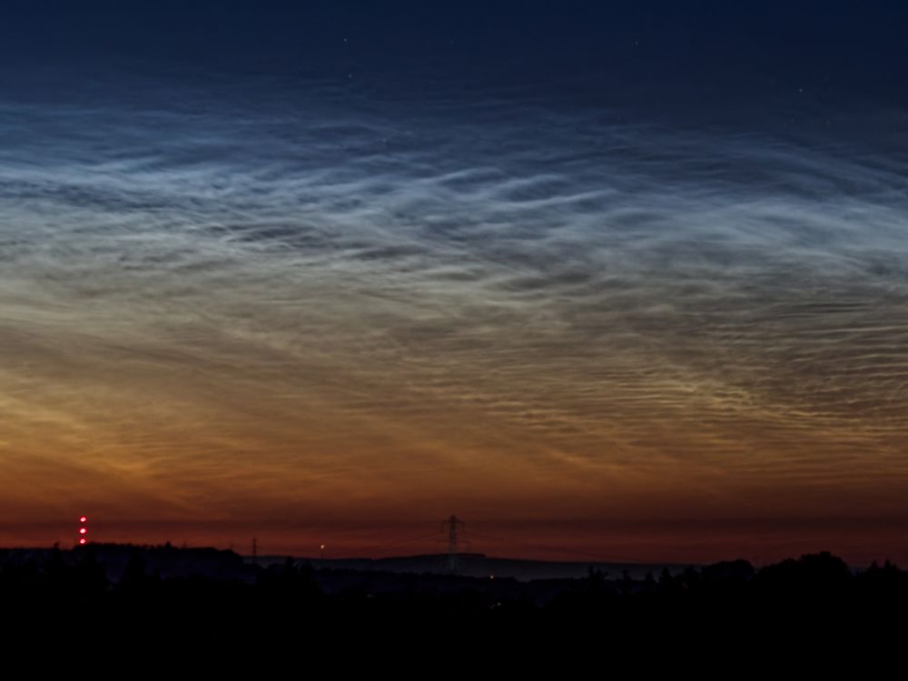 A photo of noctilucent cloud in the northern sky around midnight, showing a silhouetted landscape with orange and light blue glowing clouds against a dark blue sky.

Olympus E-M1MarkII
OLYMPUS M.40-150mm F2.8
@ƒ/2.8 40mm 1s ISO1600