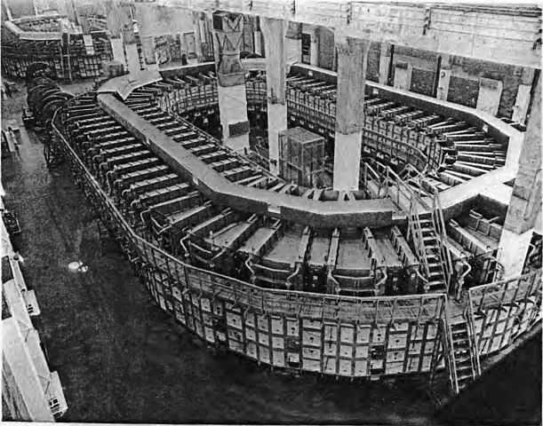 Black and white photo of the Alpha-1 racetrack at the Y-12 electromagnetic separation plant in Oak Ridge Tennessee, during the Manhattan Project. The image shows a large, circular arrangement of electromagnets used for Uranium-235 enrichment through electromagnetic separation.