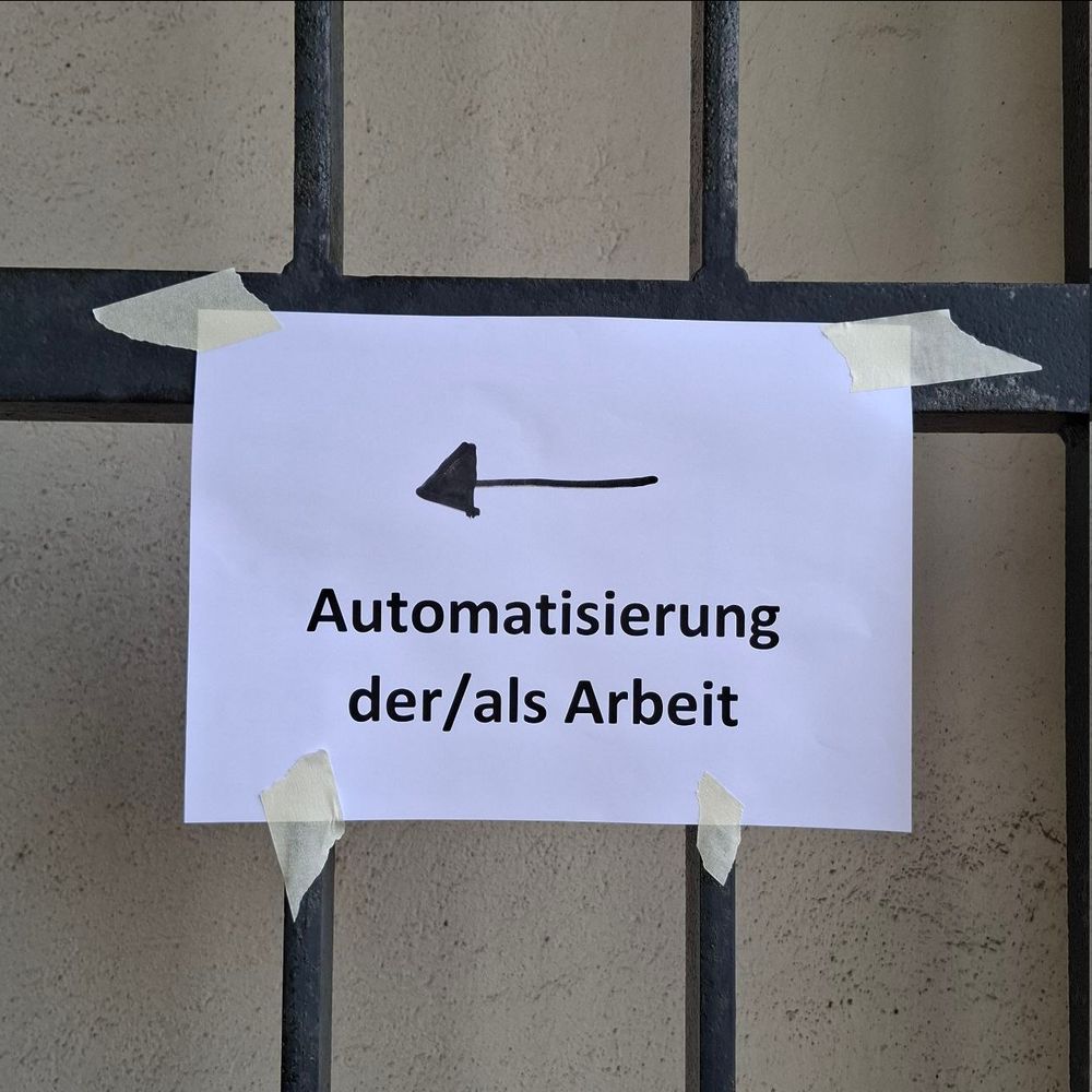 Papierschild als Wegweiser zur Tagung, mit Klebeband an einem Gitter befestigt.
