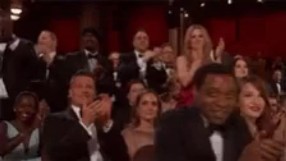 a crowd of people in tuxedos are applauding at an awards ceremony