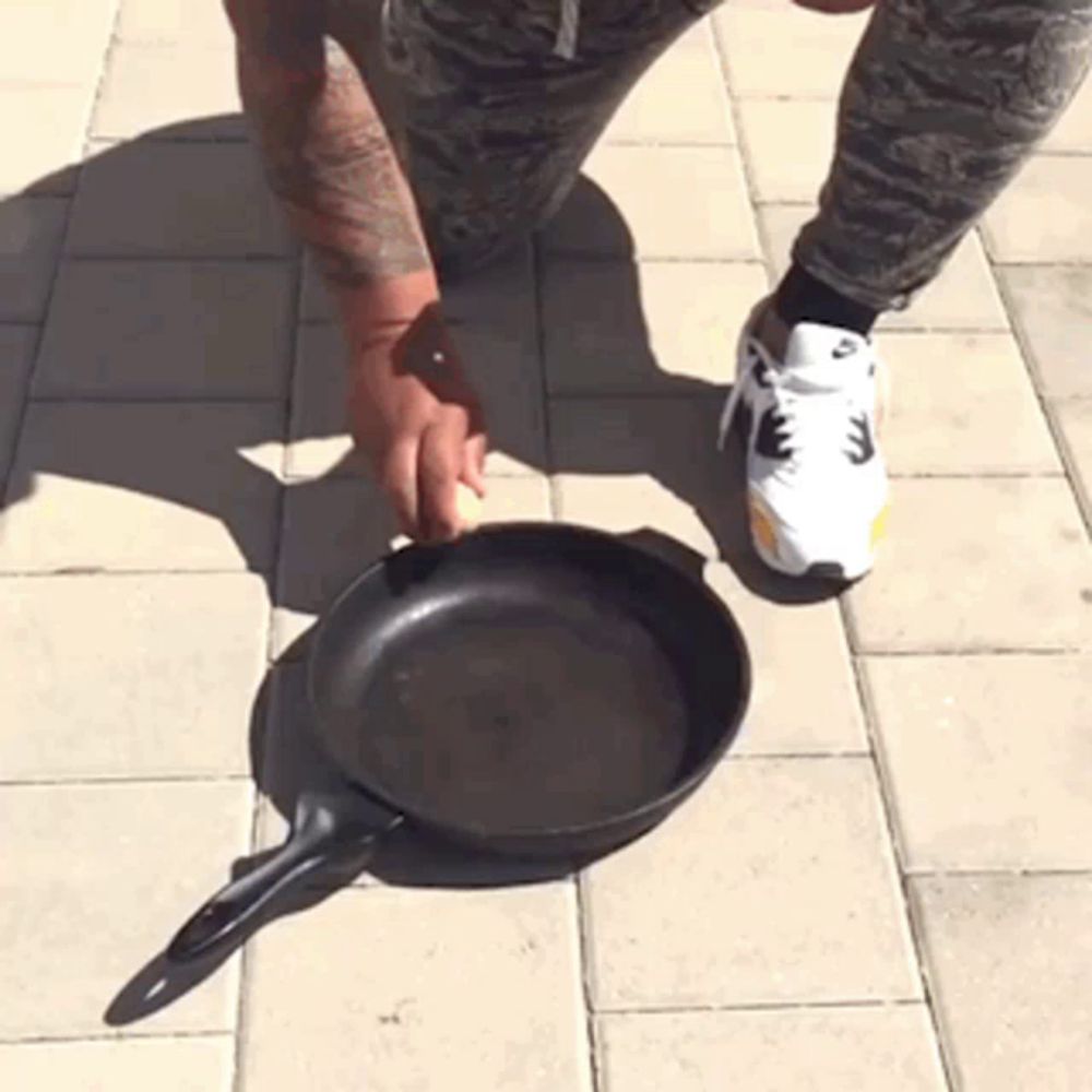 a person wearing a pair of nike shoes is kneeling down next to a frying pan