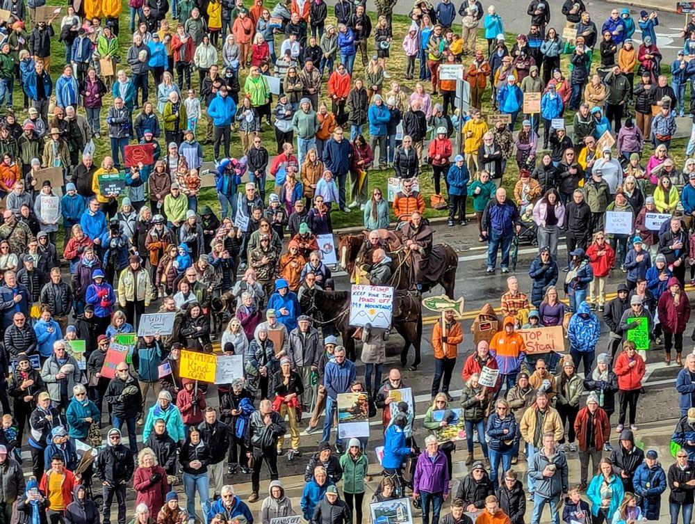 Numerous people seen from above, that have come together to support public lands at the Rally for Idaho Public Lands at the Idaho Capitol in Boise. In the center of the crowd, is a mule and a horse, both ridden by public lands supporters.