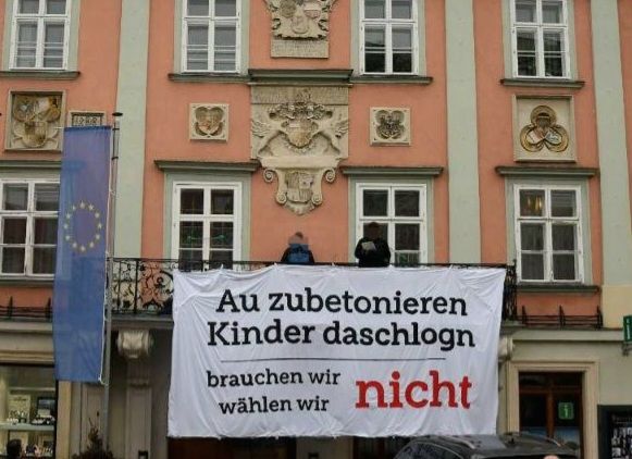 Transparent auf Rathausbalkon: "au zubetonieren, Kinder daschlogn - brauchen wir nicht, wählen wir nicht"