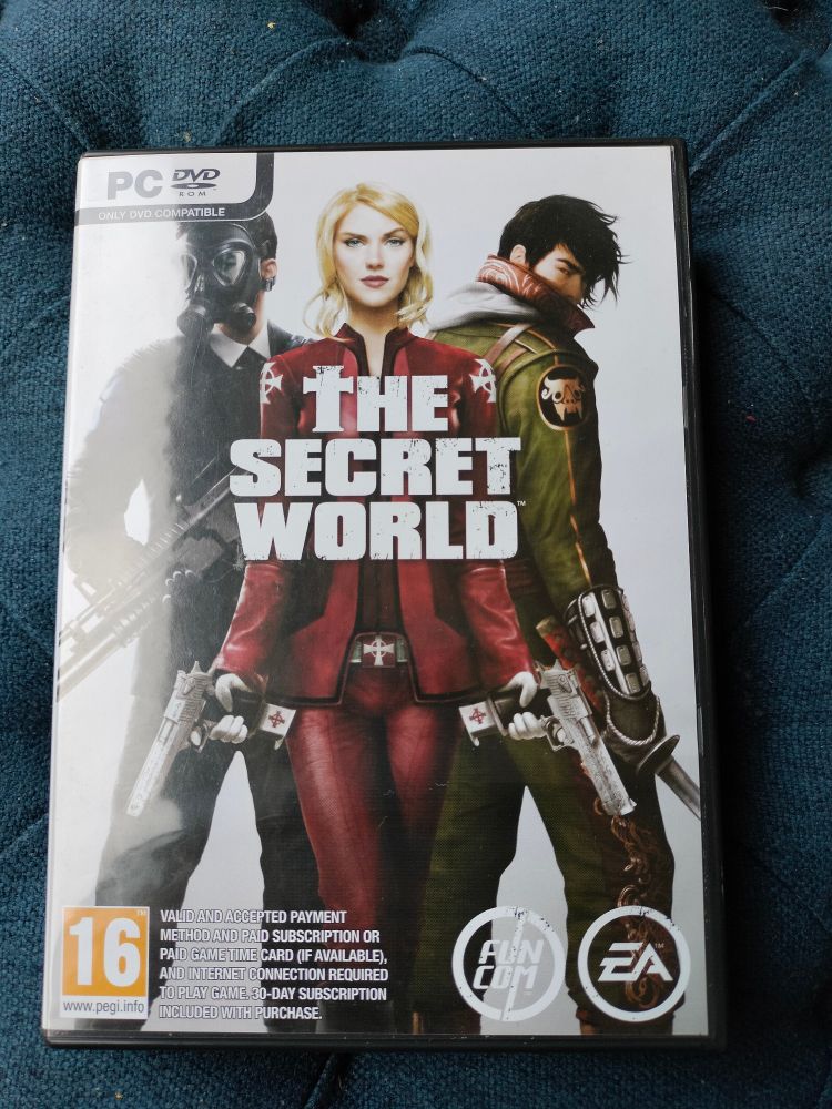 Game box for The Secret World. On the cover are the characters, on the left a man wearing a black leather suit and gas mask brandishing a rifle, in the middle a blonde short-haired woman wearing a red suit emblazoned with white cross emblems and holding pistols, and on the right a man wearing a green suit with oriental detailing and metal gauntlets, wielding a samurai sword. The words "The Secret World" is displayed in white over the top.