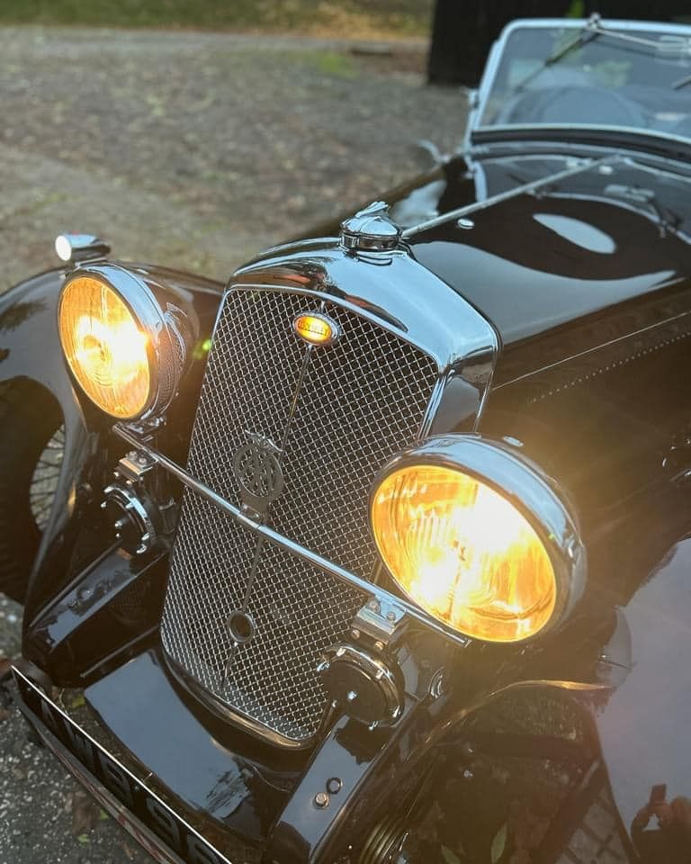 The same car seen from further back, now at an angle with it's headlights windscreen and wings visible.

The bodywork is glossy black, and the glowing badge is still visible.