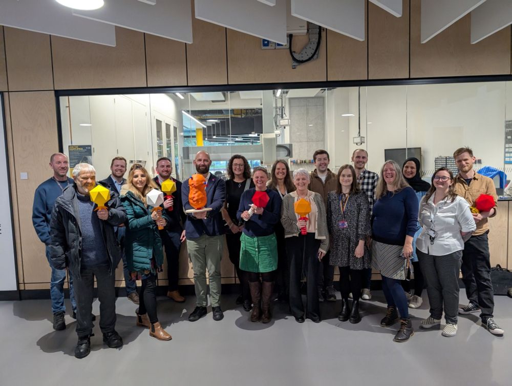 Group of staff and visitors, some holding phage models, at the University of Salford event to discuss phage.