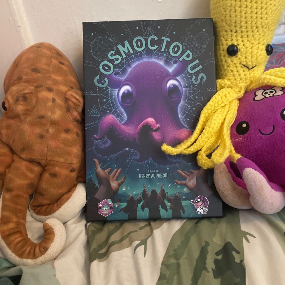 Cosmoctopus box surround by 3 octopus plushies.