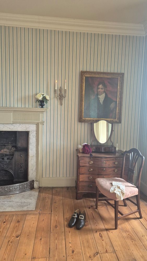 Georgian interior, striped wallpaper, portrait of a man above a chest of drawers and fireplace 