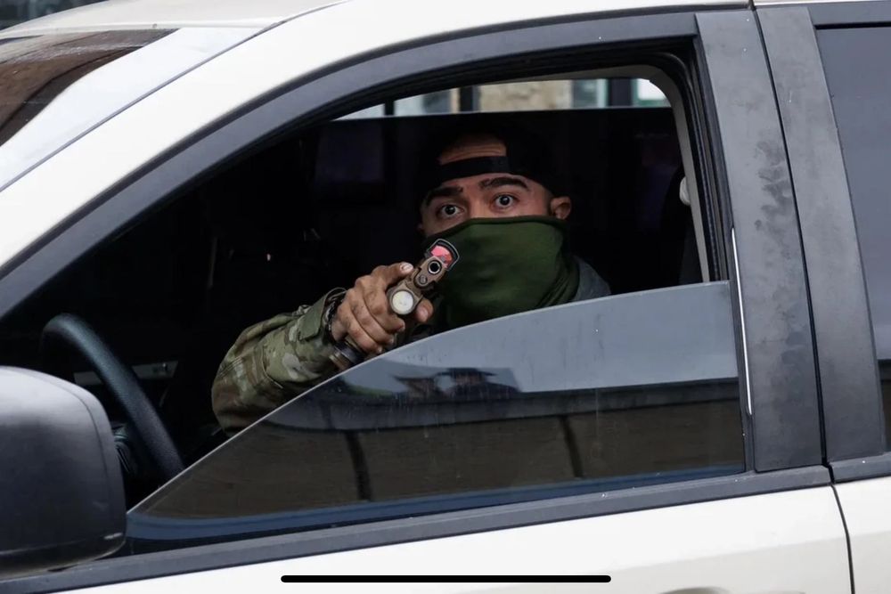 A Hispanic ice agent, his face covered by a coward's mask, pointing a gun at the camera while sitting comfortably on his fat ass in a car. His look of fear in his eyes betray his outward bravado and reveal him to be a massive, cavernous pussy. 
