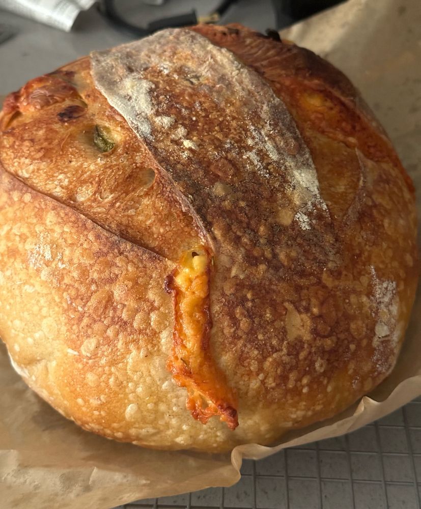 A (hopefully) delicious looking loaf of freshly baked sourdough with some cheese oozing out.  