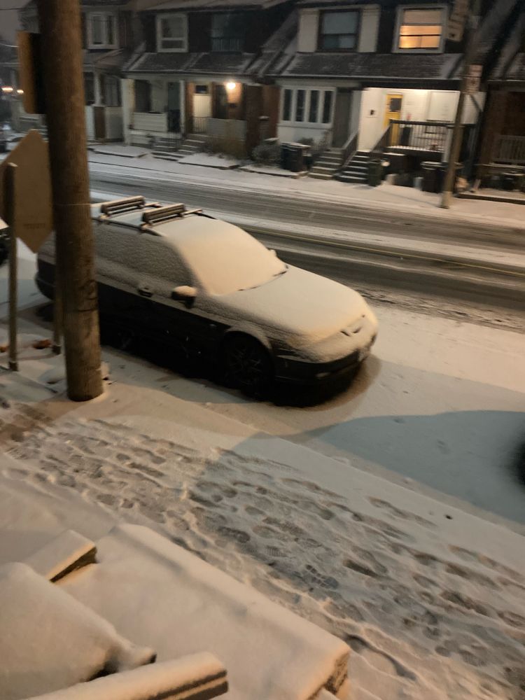 A street and cars covered in snow.