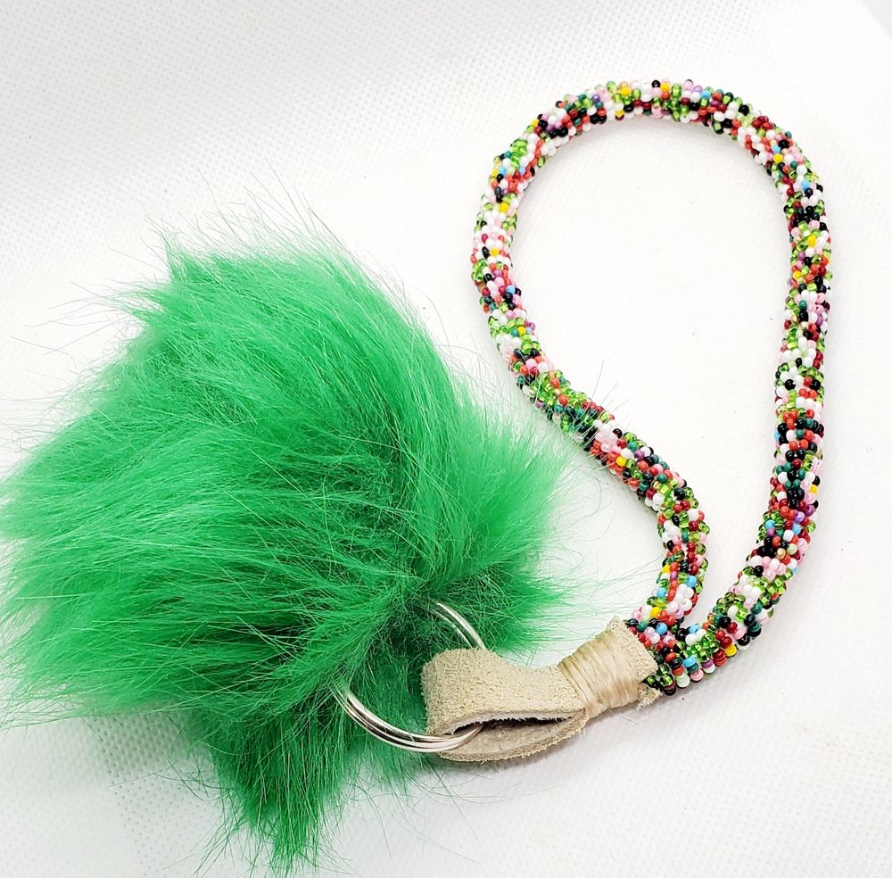 Bead wrapped keychain made with multicolored beads and a green faux rabbit poof adornment.