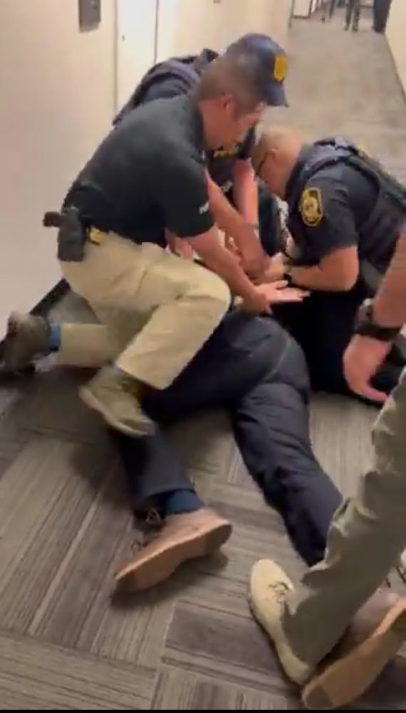 Multiple agents have thrown the senator to the ground, cuffing his hands behind his back