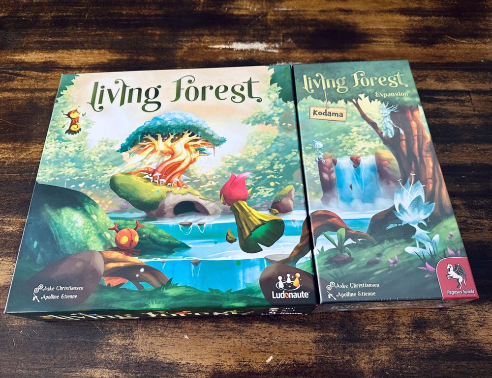 Base game Living Forest next to its expansion - the boxes placed side-by-side create an expanded scene. Whimsical fantasy.