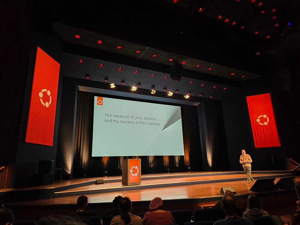 Mark Shuttleworth describing the meaning of Ubuntu with a slide saying "The measure of your success and my success, is their success"