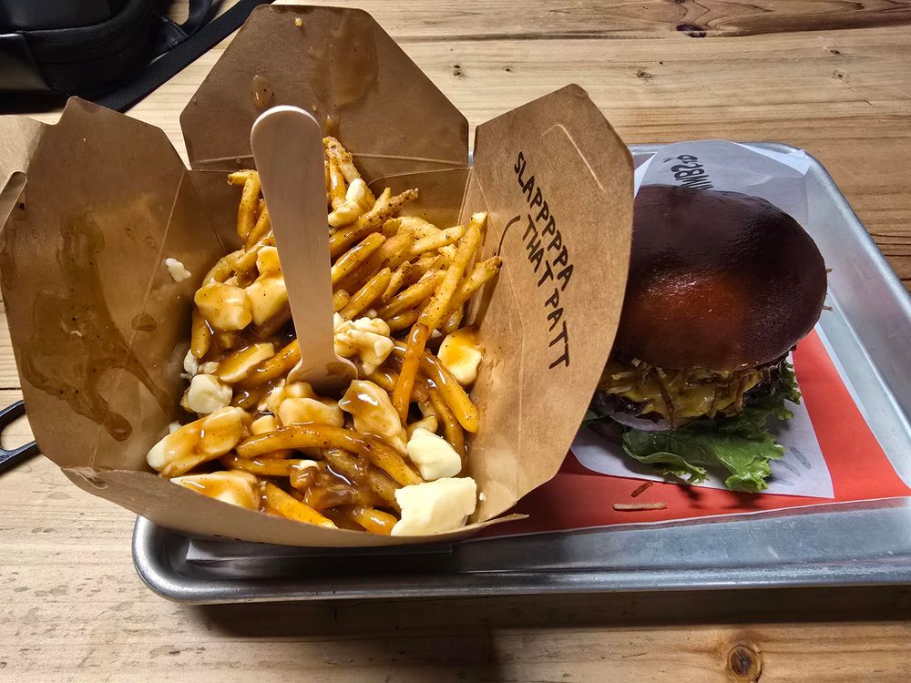 A tray with a carton of poutine and a burger