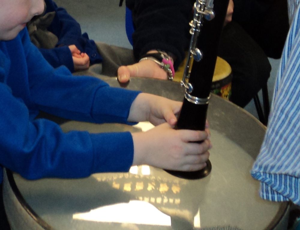 A child's hands around a clarinet. The child here is both feeling the vibrations of the clarinet and invited to respond on the drum. 