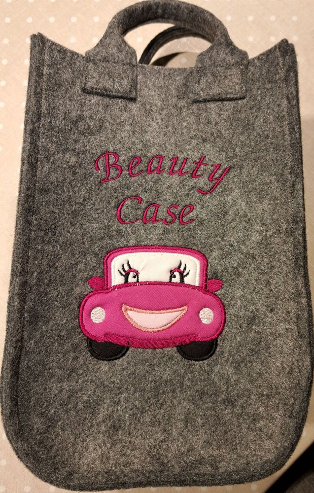 Eine Filztasche mit einem aufgestickten pinken Auto und der Aufschrift "Beauty Case" 