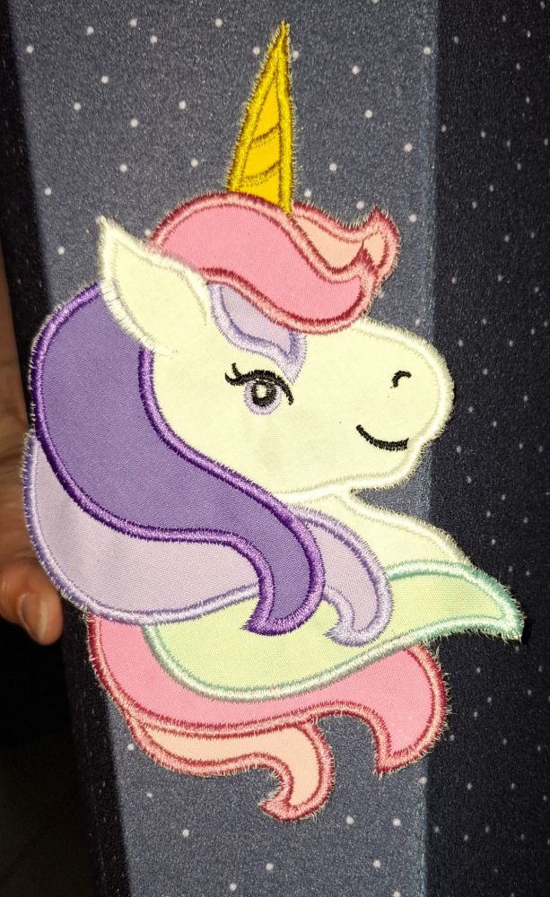 Eine Einhornapplikation mit bunter Mähne auf einer dunkelblauen Schultüte. 