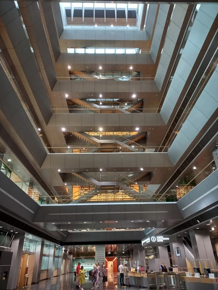 Interior foyer of a modern building with stairs and wrap-around balconies on each floor.