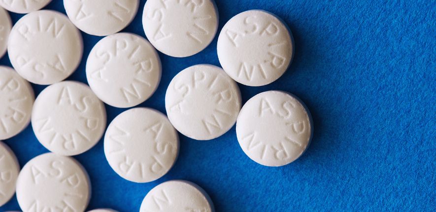 white round tablets with the letters ASPIRIN printed on them on a blue background