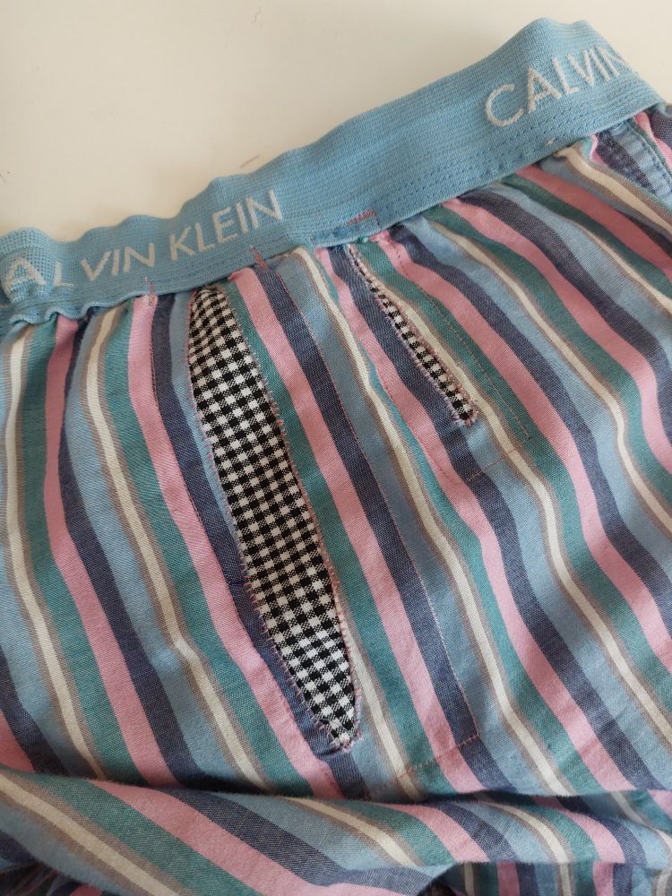 A pair of striped Calvin Klein pyjamas with 2 tears. I attached patched of black and white checked cotton underneath by hand sewing around the tears, and then used my machine to stitch around the outer edges of the patches