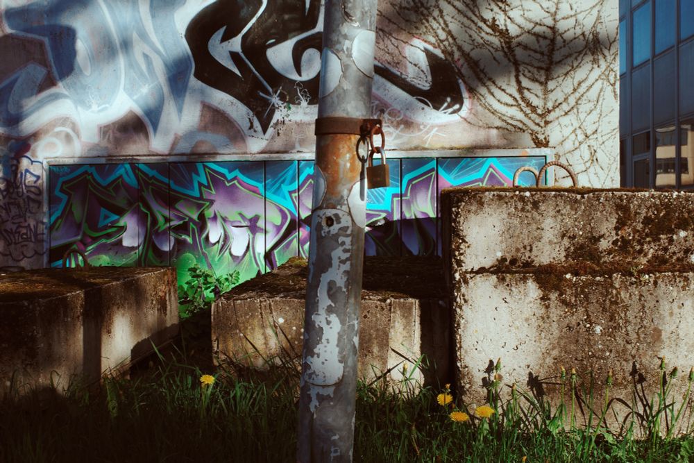 lock hanging at a light pole, light and shadows at a graffiti wall