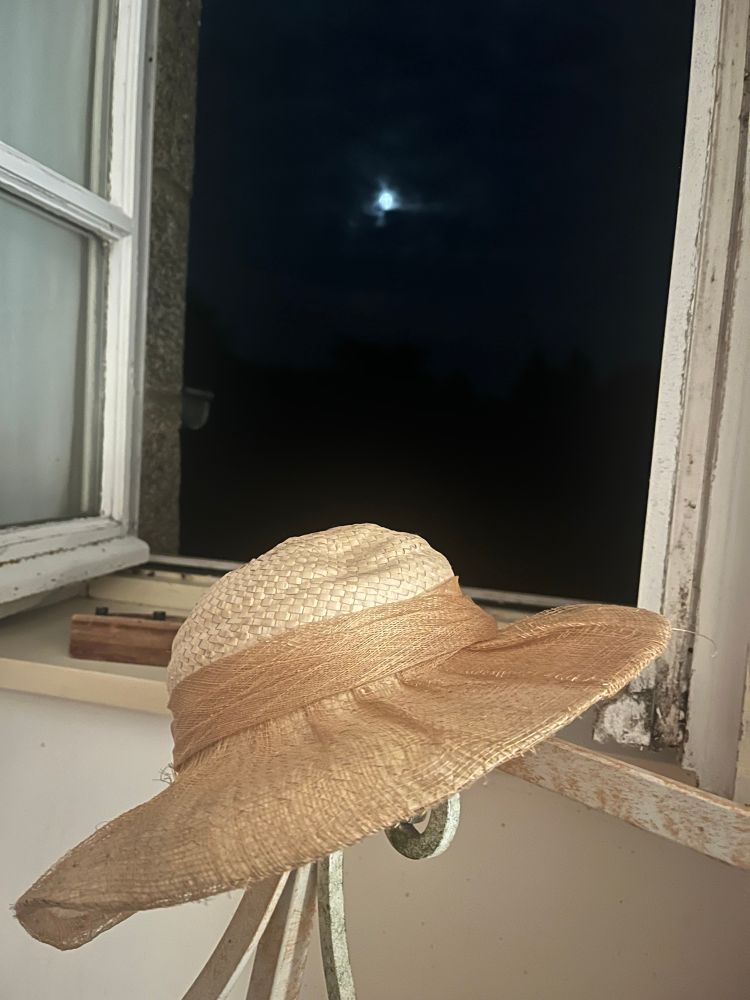 Photo d’un vieux chapeau devant une fenêtre la nuit