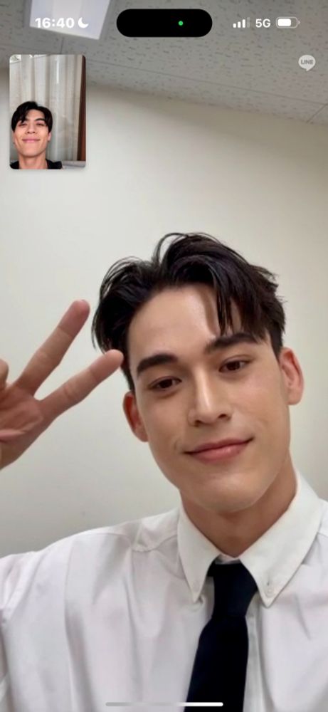 にこやかなJossさんとのビデオ通話中の画面に映るピースしているGawinさんの画像。白のボタンダウンシャツに黒のネクタイ、ステージに上がる準備がほぼ完了しているように見える。