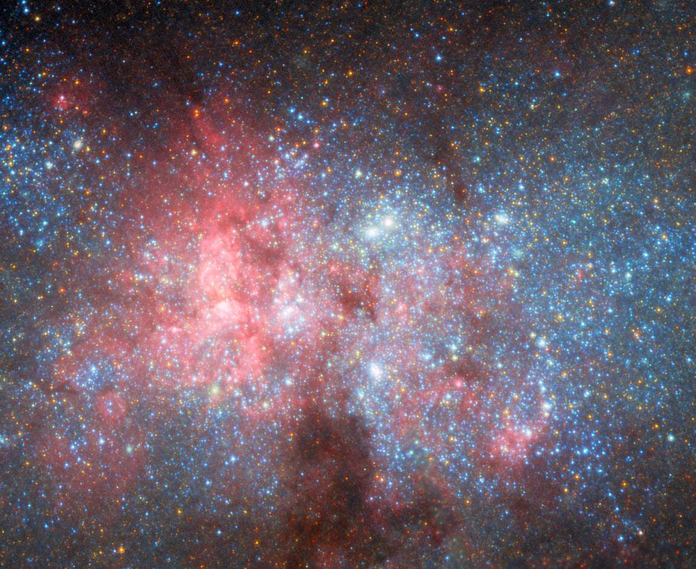The bright center of NGC 5253 galaxy filled with bright blue stars and star clusters, with gas and dust clouds in pink and dark colors. Credit: ESA/Hubble & NASA, W. D. Vacca