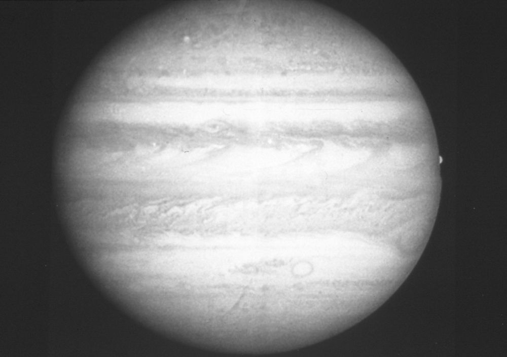 Black and white image of Jupiter showing the Great Red Spot and the satellite Europa, with detailed clouds and jet streams. Credit: NASA/ESA