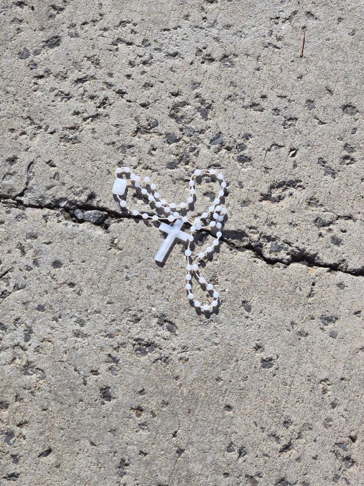 white plastic rosary on the sidewalk