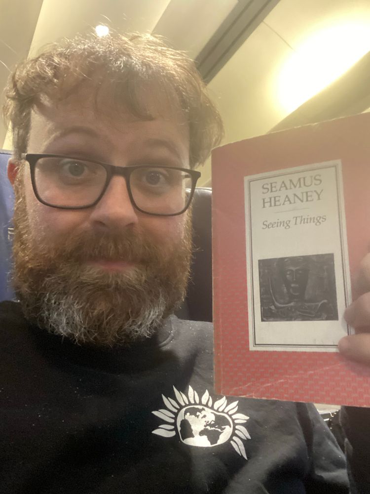 Man holding a copy of ‘Seeing Things’ by Seamus Heaney