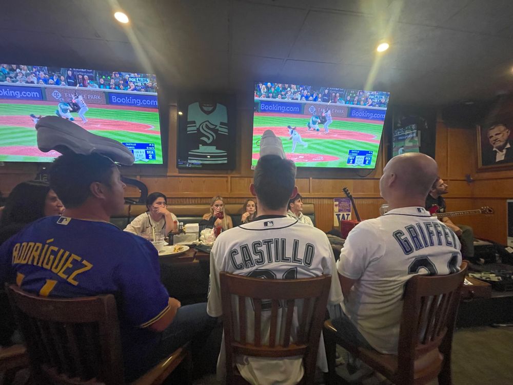 Three Mariners fans in a pub with their shoe on their heads for good luck.