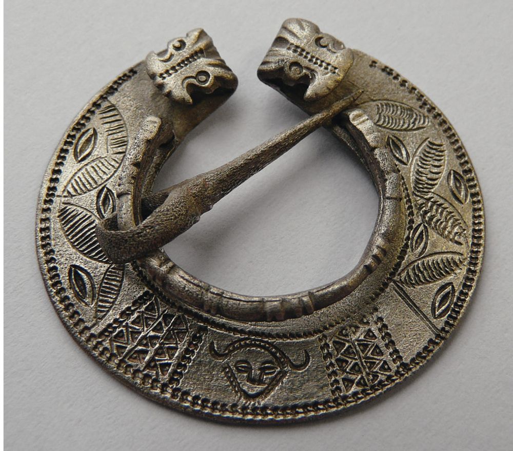 A silver quoit brooch decorated with punched and incised geometric and humanoid motifs