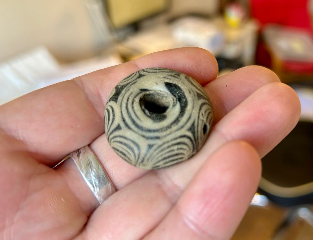 An Anglo-Saxon sword bead made of glass with black and white ornamentation.