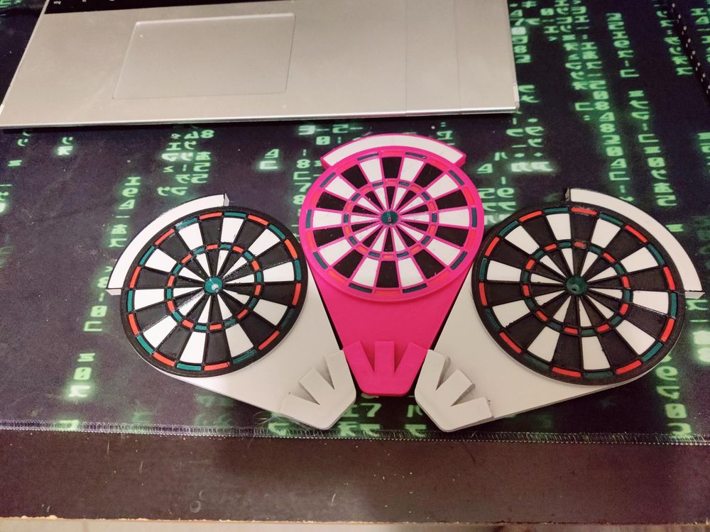 Three dart holders in the shape of dart boards. The middle one is screaming pink