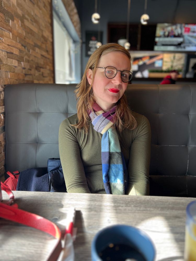 Beautiful cutie mb is sitting in a sunny booth at a diner, smiling