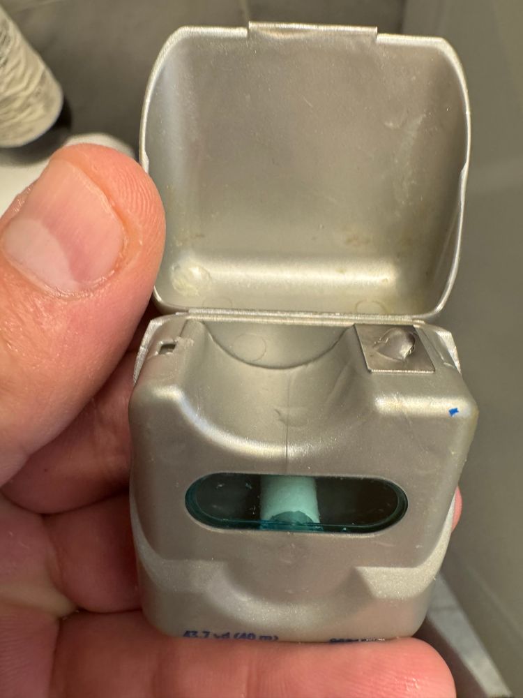 an empty dental floss container 