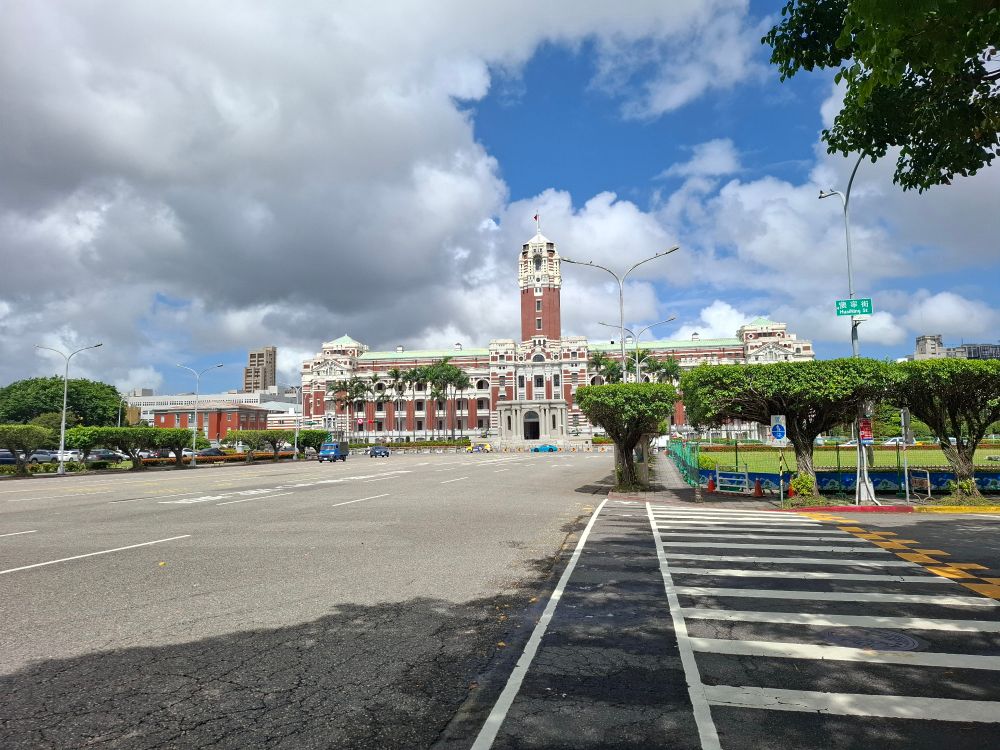 Large, wide street and an important looking brown and white gov building 