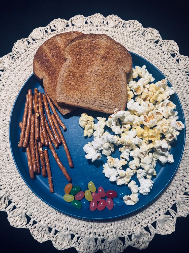 Snoopy’s Thanksgiving meal. A blue plate with toast, pretzel sticks, jelly beans, and popcorn