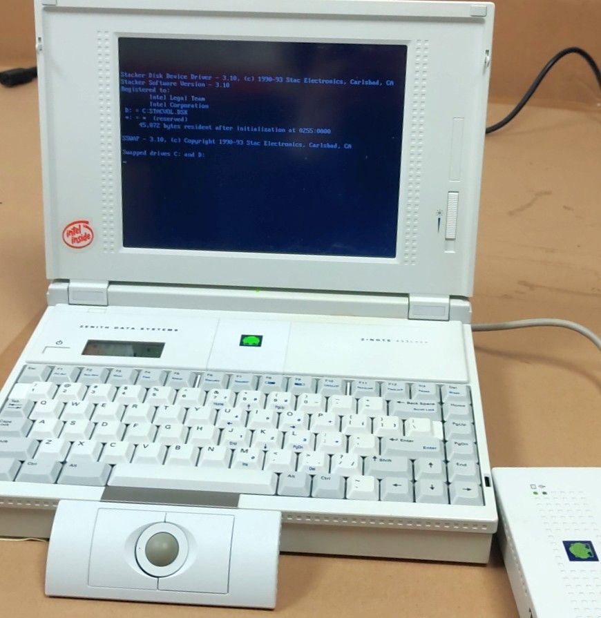 A Zenith Data Systems laptop from the early 1990s with a trackball attachment, seen booting to MS-DOS.