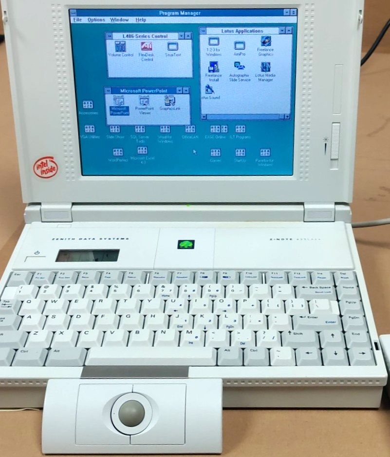 A Zenith Data Systems laptop from the early 1990s with a trackball attachment, showing a customised Windows 3.1 Program Manager.