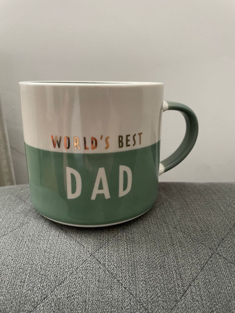 A “World’s Best Dad” mug. It is top half cream and bottom half sage.